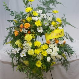 Standing floral spray with yellow, white, and orange flowers on an easel