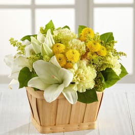 White lilies and yellow mums in a wooden basket