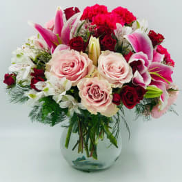 Mixed bouquet of pink lilies, roses, and carnations in a glass vase