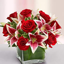 Red roses and pink lilies arranged in a square glass vase