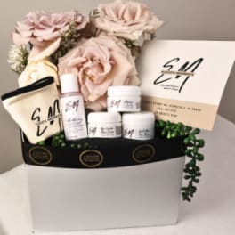 Gift box with pink roses, skincare items, and a card