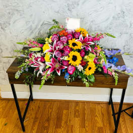 Large mixed flower arrangement with roses, lilies, and sunflowers on a table