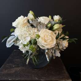 White roses and hydrangeas arranged in a dark vase
