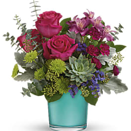 Pink roses and purple flowers in a turquoise glass vase