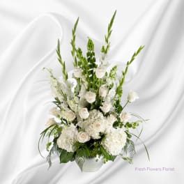 Tall white floral arrangement in a white vase with roses and snapdragons