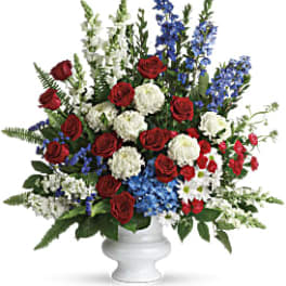 Red roses, white mums, and blue flowers in a white vase