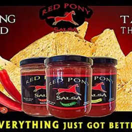 Three jars of salsa with tortilla chips and red peppers on a red background