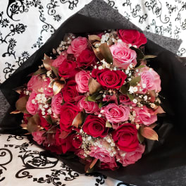 Bouquet of pink and red roses wrapped in black paper