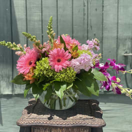 Pink gerbera daisies and orchids in a glass vase