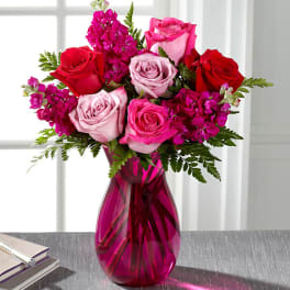 Pink and red roses in a magenta glass vase
