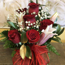 Red roses and pink lilies arranged with baby's breath in a red ribbon wrap