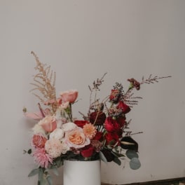 Pink and red rose arrangement in a white cylindrical vase