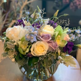 Mixed bouquet of white, lavender, and purple flowers in a glass vase