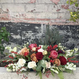 Low floral arrangement with roses, protea, and red berries