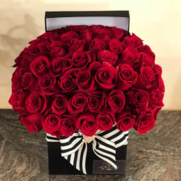 Boxed arrangement of red roses with a black-and-white striped ribbon