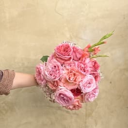 Handheld bouquet of pink roses with coral accents