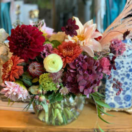 Mixed bouquet in a glass vase with burgundy, peach, and cream blooms