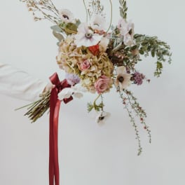 Loose bouquet of pale flowers with a red ribbon tie