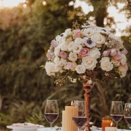 Pink and white rose centerpiece on a copper stand at a candlelit table