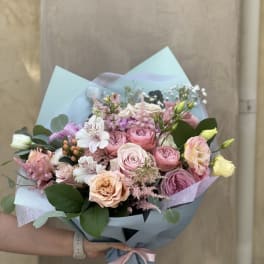 Handheld bouquet of pink and white roses with pastel wrapping