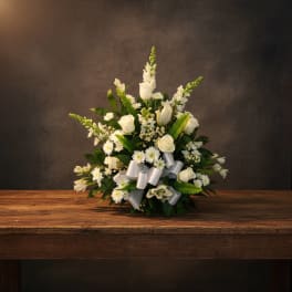 White floral arrangement with a silver ribbon on a wooden table