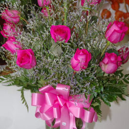 Pink roses in a clear glass vase with a pink ribbon bow
