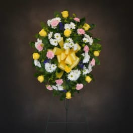 Standing floral wreath with yellow roses, white daisies, and pink carnations