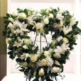 Heart-shaped white floral wreath on a stand