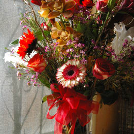 Mixed bouquet in a tall glass vase with a red ribbon
