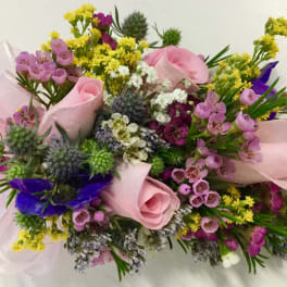 Bouquet of pink roses, purple flowers, and yellow filler tied with a pale ribbon