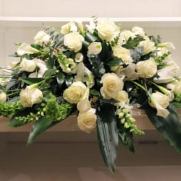 White rose and calla lily arrangement with greenery in a low container