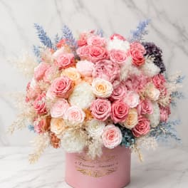 Pink and white rose arrangement in a round pink box