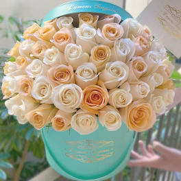 Bouquet of cream and peach roses in a turquoise hat box