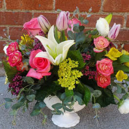 Mixed bouquet in a white pedestal vase with pink roses and white lilies