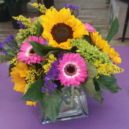 Bouquet of sunflowers and pink gerbera daisies in a glass vase