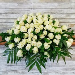 Large bouquet of white roses with green foliage on a wooden surface