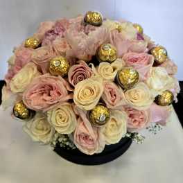 Bouquet of pale pink and cream roses with gold-wrapped chocolates in a black box