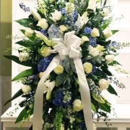 Tall white and blue floral standing spray with a ribbon bow