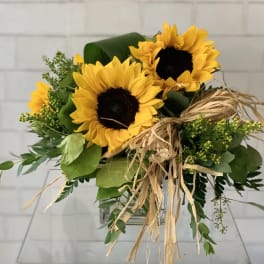Sunflower bouquet with a raffia bow in a clear glass vase
