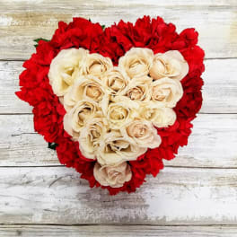 Heart-shaped bouquet of cream roses surrounded by red carnations