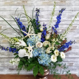 Blue and white floral arrangement in a bronze vase with starfish accents