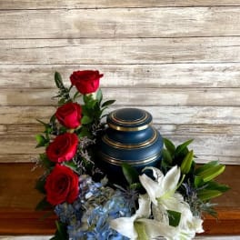 Red roses and white lilies arranged around a blue urn