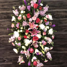Large standing floral spray with pink lilies, red roses, and purple blooms