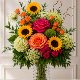 Mixed bouquet of roses and sunflowers in a clear glass vase