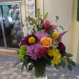 Mixed bouquet with lilies, roses, chrysanthemums, and alstroemeria in a glass vase