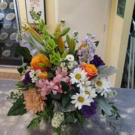 Mixed bouquet with lilies, roses, daisies, and purple blooms in a vase