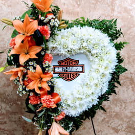 Heart-shaped floral wreath with orange lilies and white chrysanthemums around a Harley-Davidson logo