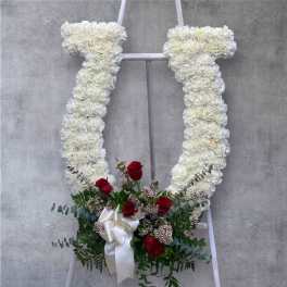 White floral standing spray with red roses and a white ribbon