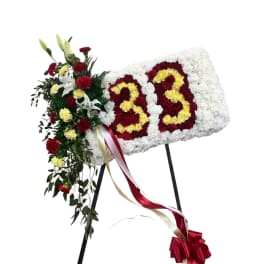 Floral standing tribute with white, red, and yellow flowers on an easel