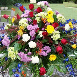 Large mixed floral spray with red roses, yellow daisies, and purple blooms